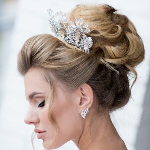 Beautiful blonde bride with high hair-do and precious silver wreath on her hair