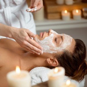 Young beautiful brunette girl in mask for face relaxing in spa salon. Eyes closed. Copy space.